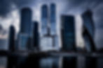low-angle-shot-grey-skyscrapers-front-river-dark-cloudy-sky.jpeg