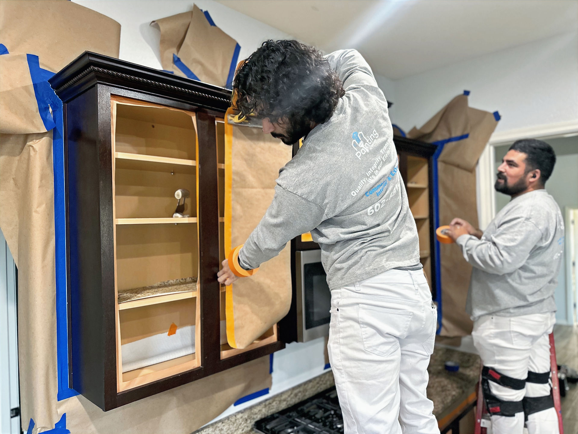 Kitchen cabinets masked off with protective paper and tape before professional cabinet painting.