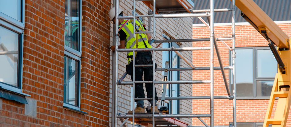 Construction workers using aluminium mobile scaffold tower and safety harness to work at height. Working at height safety regulation