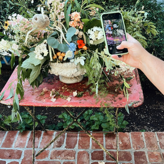 BTS taking photographs of a frecnh urn floral arrangement