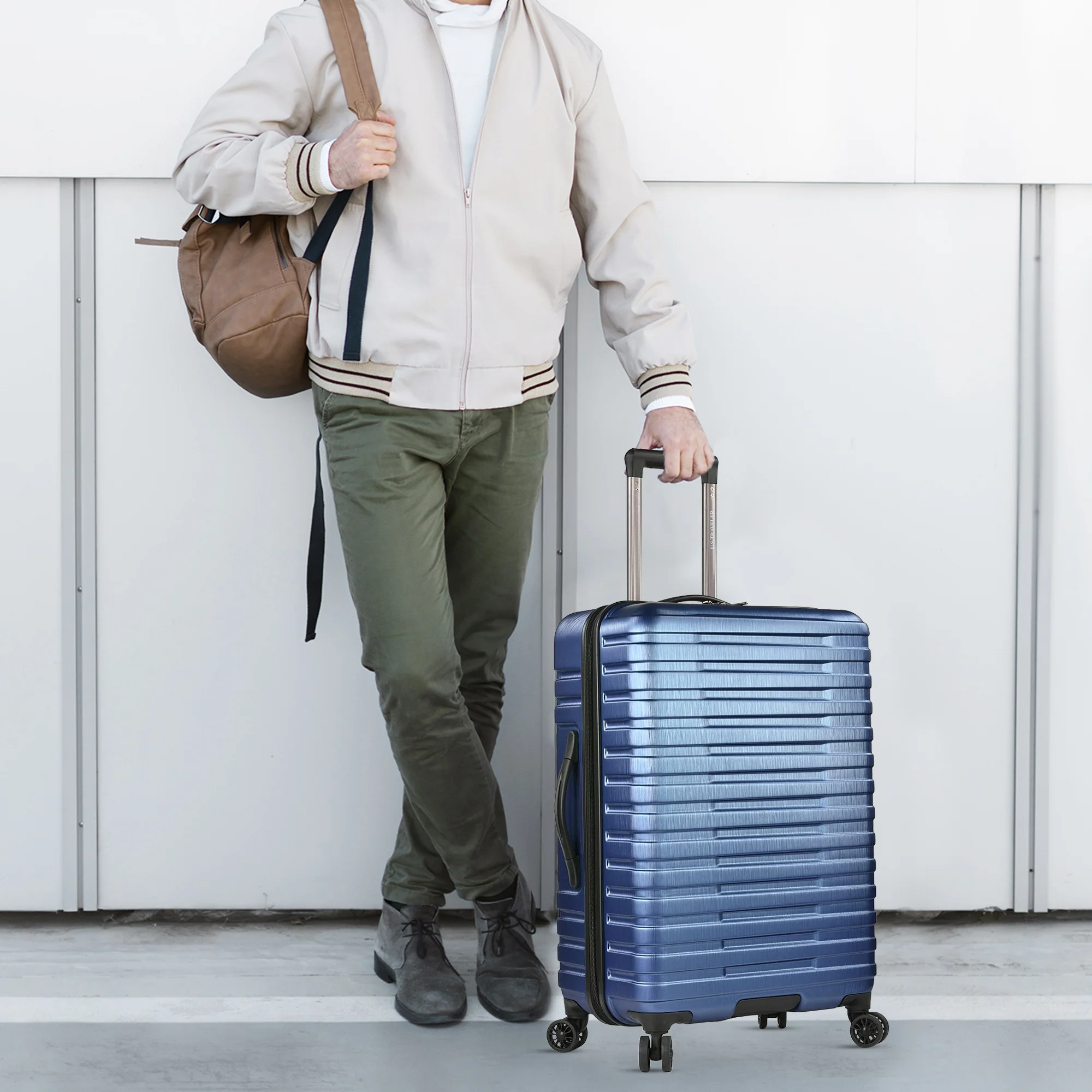 Traveler holding a bag and standing next to a suitcase