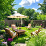 A well-landscaped Wichita backyard patio with patio furniture and an umbrella, highlighting the importance of mosquito control during peak summer heat.