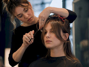 Stylist trimming centre-parted curtain bangs