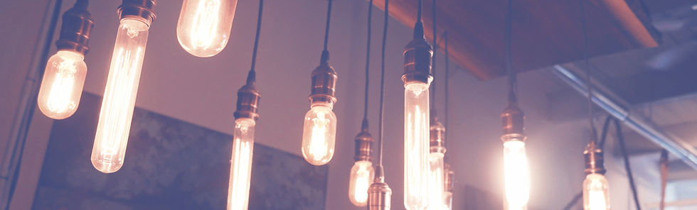 A dimly lit room with mulitple Edison light bulbs hanging from ceiling