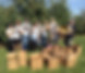 Volunteers at an apple orchard wearing Broadway Serves shirts and holding up apples, behind boxes of apples