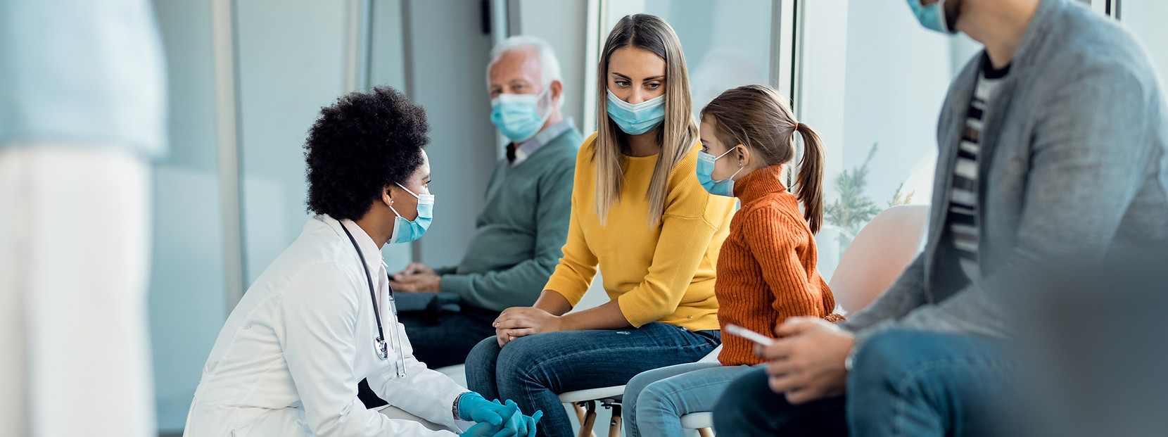 mother-daughter-talking-african-american-doctor-while-wearing-face-masks-hospital-waiting-
