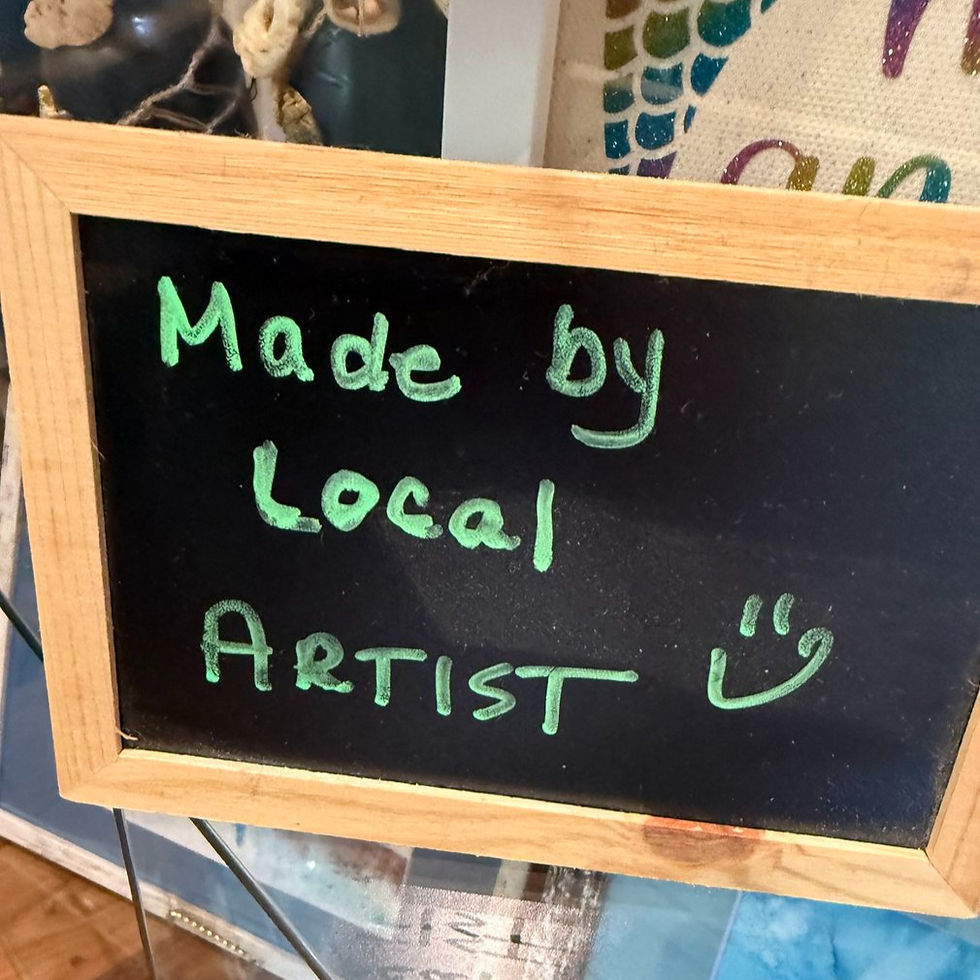 A small chalkboard sign with green writing Advertisting 'made by a local artist'