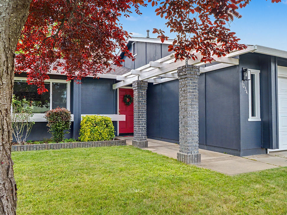 Modern home exterior with dark siding, red front door and stone entry details in Redding, California.