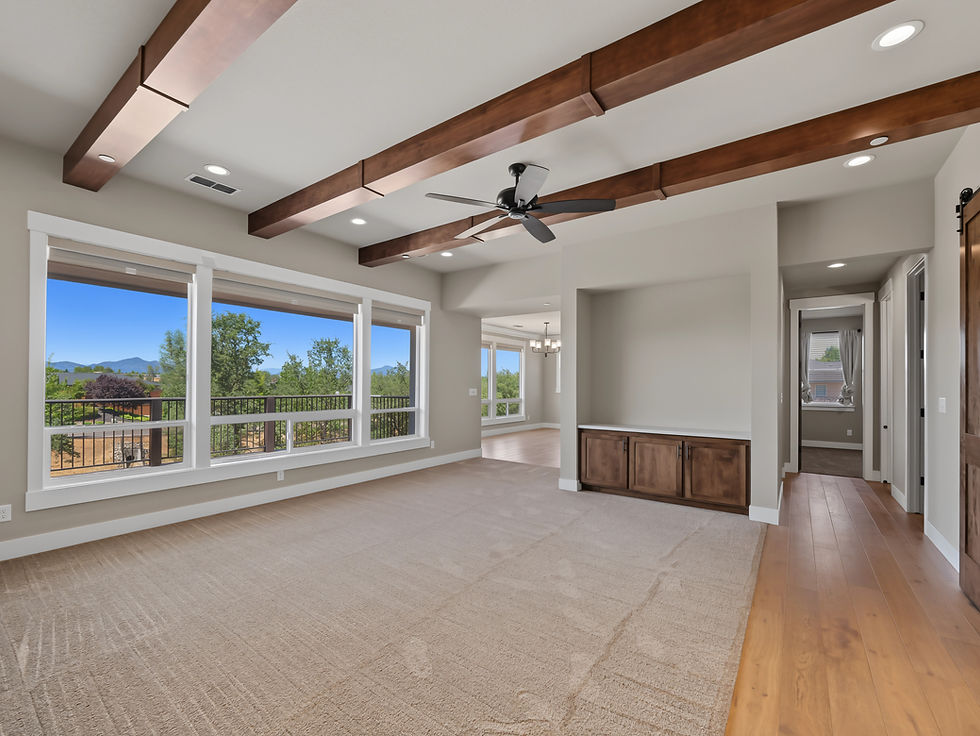 Bright interior room with exposed wood beams and wide windows overlooking the property.