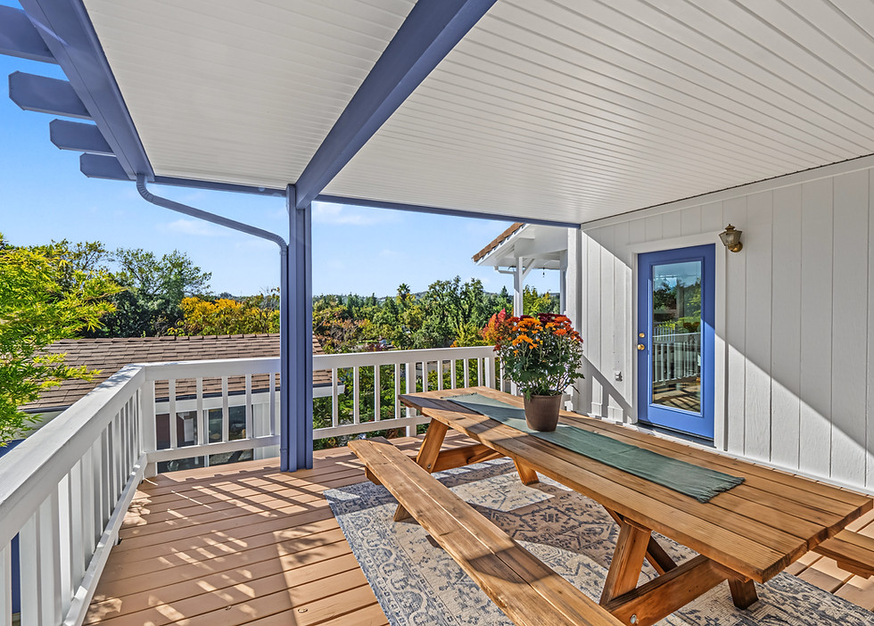 Covered outdoor deck with seating overlooking a wooded residential property in Shasta County.