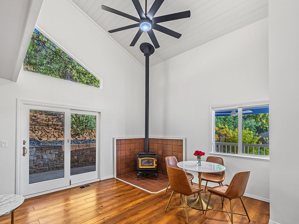 Bright interior with hardwood floors, large windows and a freestanding stove in a residential property.