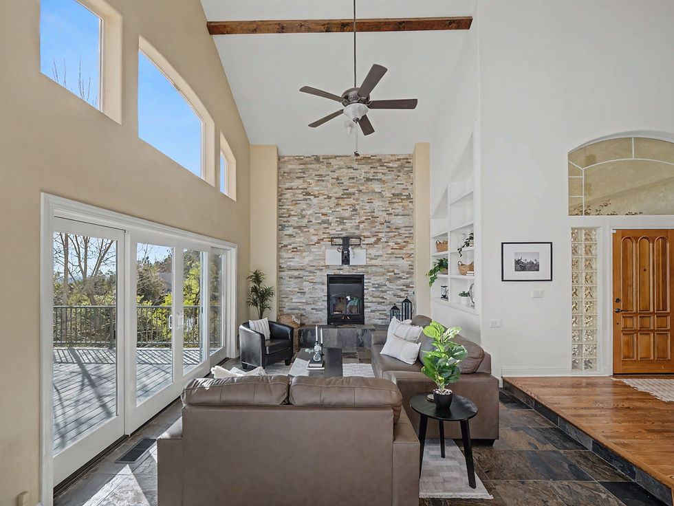 Living room with vaulted ceiling, stone fireplace and large windows in a Redding, California home.