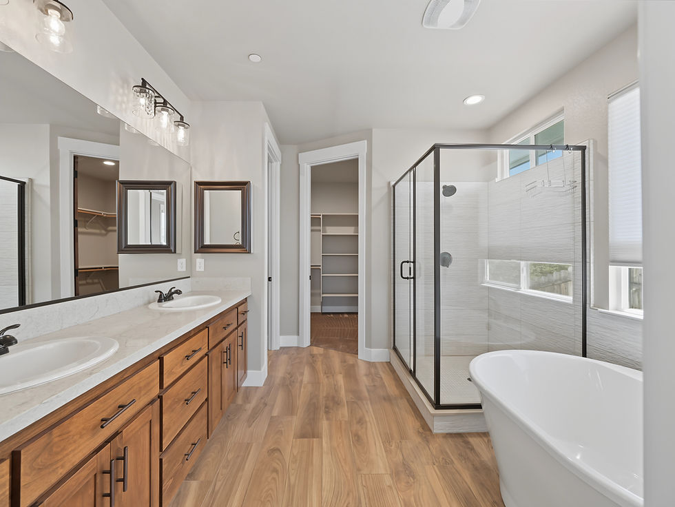 Spacious bathroom with double vanity, glass shower and freestanding tub photographed for real estate marketing.