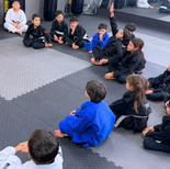 Young students in Brazilian Jiu Jitsu class, sitting in circle during learning time