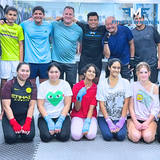 Group of people posing together, Fitness In Motion logo, smiling, happy faces.
