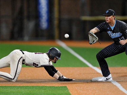 Youth baseball player diving back to first base during a competitive night game, with the first baseman preparing to receive the throw — capturing the explosive athleticism and quick-twitch reactions that make IV hydration therapy essential for young baseball players in Bridgewater and across New Jersey