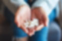Closeup image of a woman holding white medicine capsules in hands.jpg