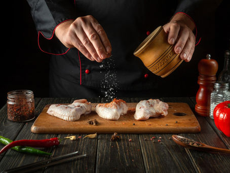 A person salting a chicken