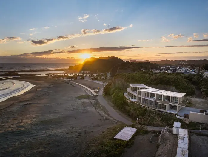 HOTEL THE MADO,千叶夷隅,夕阳下的太东海岸与酒店同框,建筑在海湾转折处形成轻微的水平线。
HOTEL THE MADO, Isumi, Chiba: The hotel appears as a low horizontal line beside the curve of Taitō Beach at sunset.