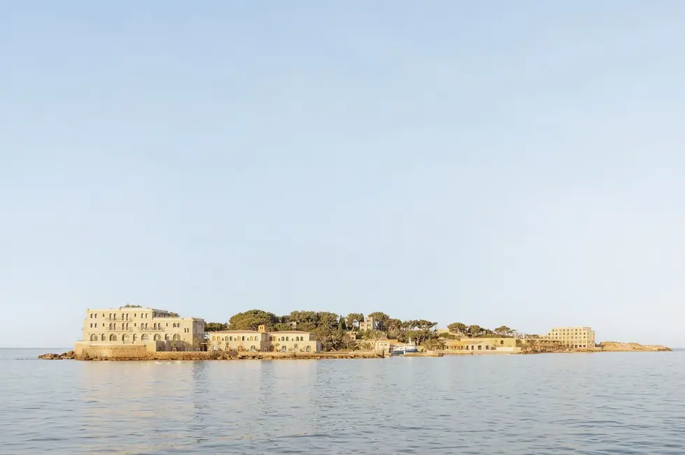 Zannier本多尔岛整体项目外观,从海上望向更新后的本多尔岛,白色建筑沿地形层层展开,港口、松林与低矮屋面共同保持地中海聚落的尺度
Zannier Île de Bendor overall island view: Seen from the water, the renewed Île de Bendor rises as a layered white settlement, with harbour, pines and low roofline