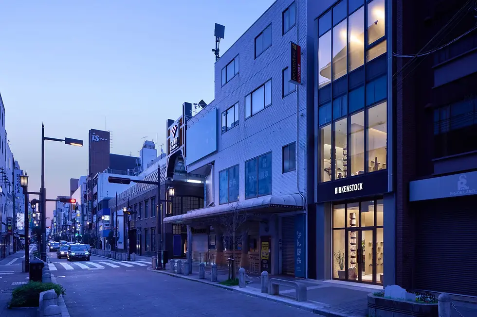 BIRKENSTOCK心斋桥概念店整体项目的外观,从北侧道路望向店铺,通高玻璃在密集商业街景中展示两层连续的零售空间。
BIRKENSTOCK SHINSAIBASHI / TORAFU ARCHITECTS, Seen from across the northern street, full-height glazing reveals the two retail floors as a continuous interior within the dense shopping district.