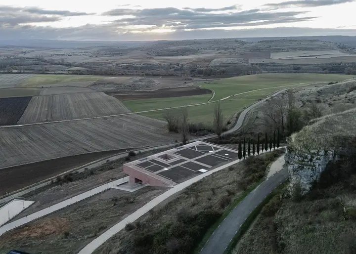 从高原回望,覆土建筑以低矮矩形嵌入农田与岩壁之间
Seen from the plateau, the planted building lies as a low rectangle between farmland and the rocky escarpment
