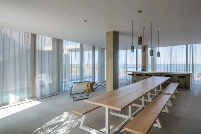 HOTEL THE MADO,千叶夷隅,长桌置于通透的公共餐饮空间中,柱网与玻璃边界共同框住海面。
HOTEL THE MADO, Isumi, Chiba: A long communal table sits within the glazed dining room, looking toward the sea.