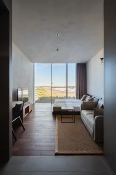 HOTEL THE MADO,千叶夷隅,一间狭长客房在尽端打开海景,床和座椅沿视线方向依次布置。
HOTEL THE MADO, Isumi, Chiba: A narrow guest room aligns bed and seating with the ocean view at its far end.