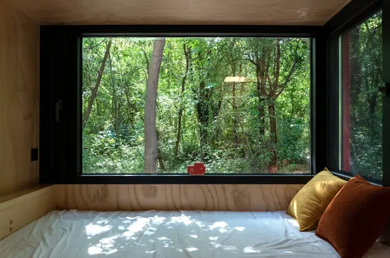 红色潜水艇小屋:从床位望向大窗,树林成为室内最宽阔的一幅画面。
Red Submarine Cabin: From the bed, the picture window gives the forest its broadest frame.