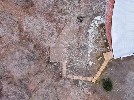 THE CONE轻井泽共享别墅 从场地上空看向建筑东南侧 深远挑檐与连续玻璃共同面向森林
THE CONE shared villa in Karuizawa, The southeast side pairs a deep eave with continuous glazing facing the forest