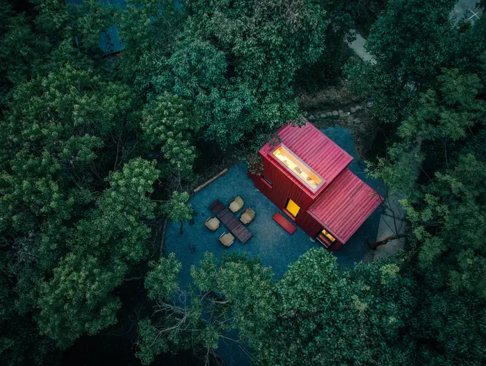 红色潜水艇小屋:从高处回望,红色小屋成为林地中的鲜明坐标。
Red Submarine Cabin: From above, the red cabin appears as a distinct marker in the woodland.