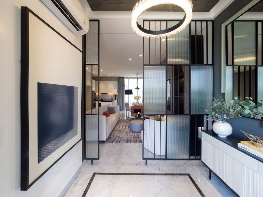 Modern entryway foyer featuring fluted glass partition screens, a minimalist console table, and a statement round chandelier.
