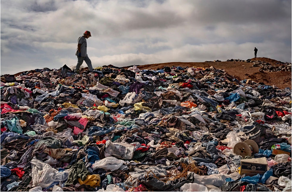 A man walks on a huge mound of trash.