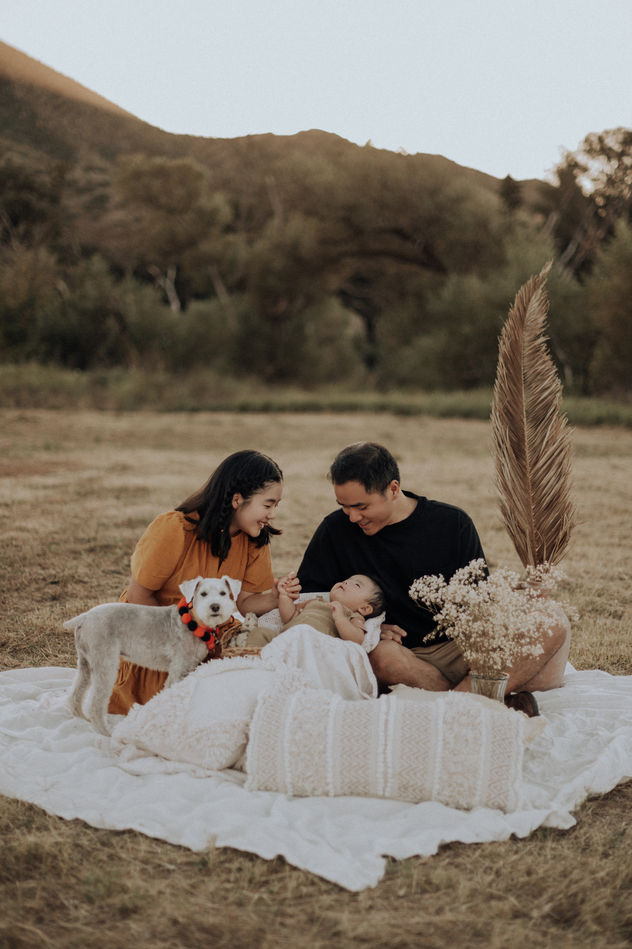 A beautiful lifestyle family photography session in Malibu, featuring parents and their newborn lying on a cozy, textured blanket in an open field at Paramount Ranch. Los Angeles portrait photographer capturing authentic family love.