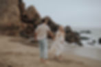 Romantic maternity session at Point Dume in Malibu with a couple walking along the rocky beach at sunset.