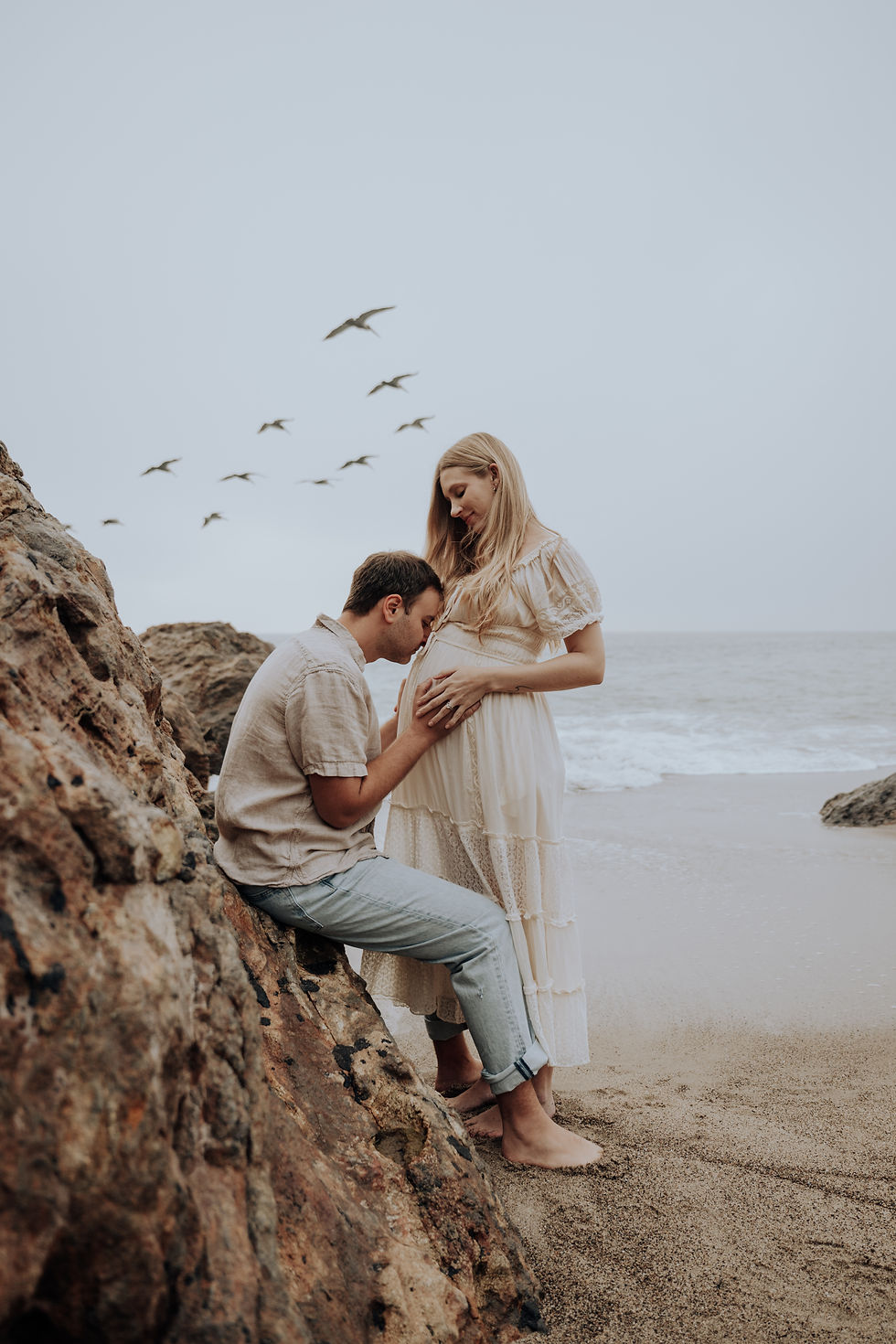 Expecting father kissing the baby bump during a maternity session at Point Dume beach in Malibu.