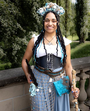 Eine junge Frau mit langen Zöpfen in einem mittelalterlichen Fantasykostüm.