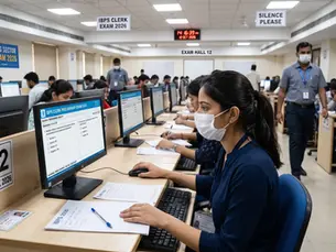 A young woman in a mask takes an IBPS Clerk 2026 computer-based exam in a busy, monitored hall.
