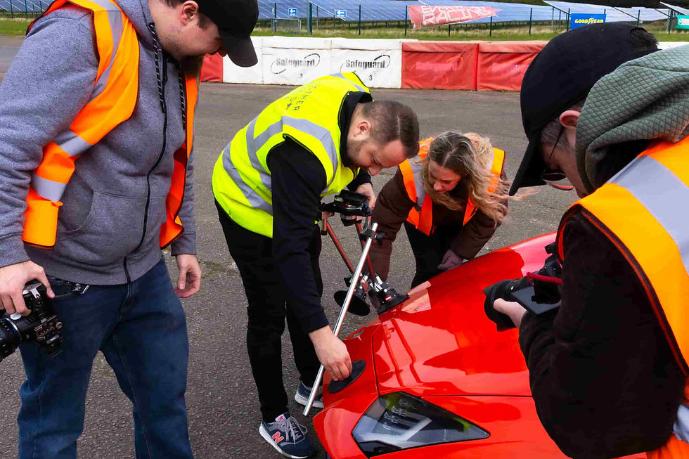 Another World Media crew prepares equipment on a sleek sports car at Everyman Racing in Leicester, gearing up for an exciting shoot.