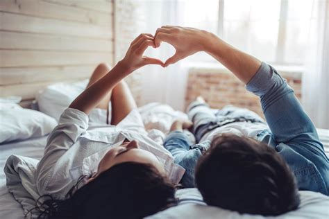 Couple in bed making heart together with their hands