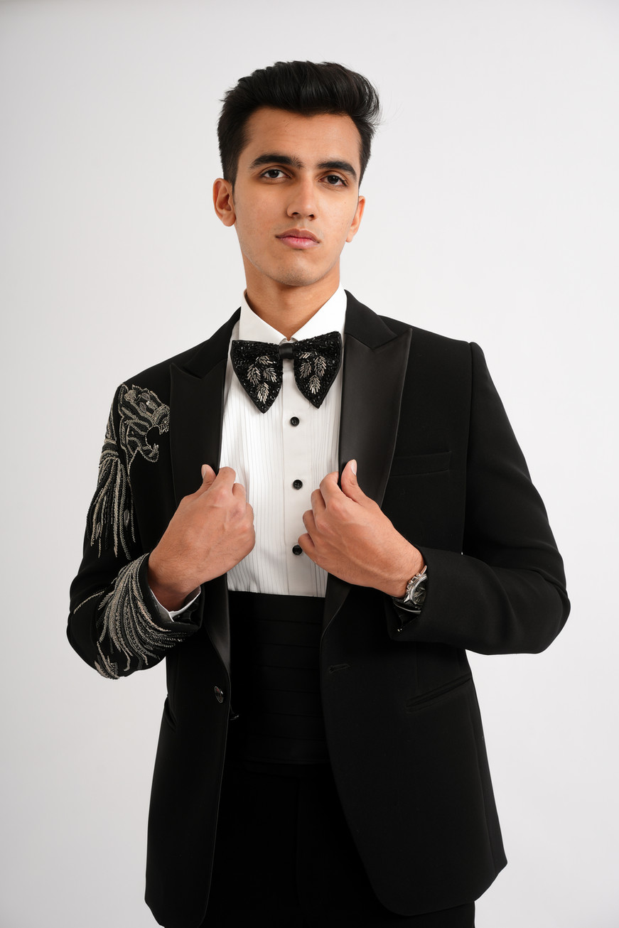 Close-up of a black designer tuxedo showcasing the intricate lion motif embroidered across the shoulder and sleeve.