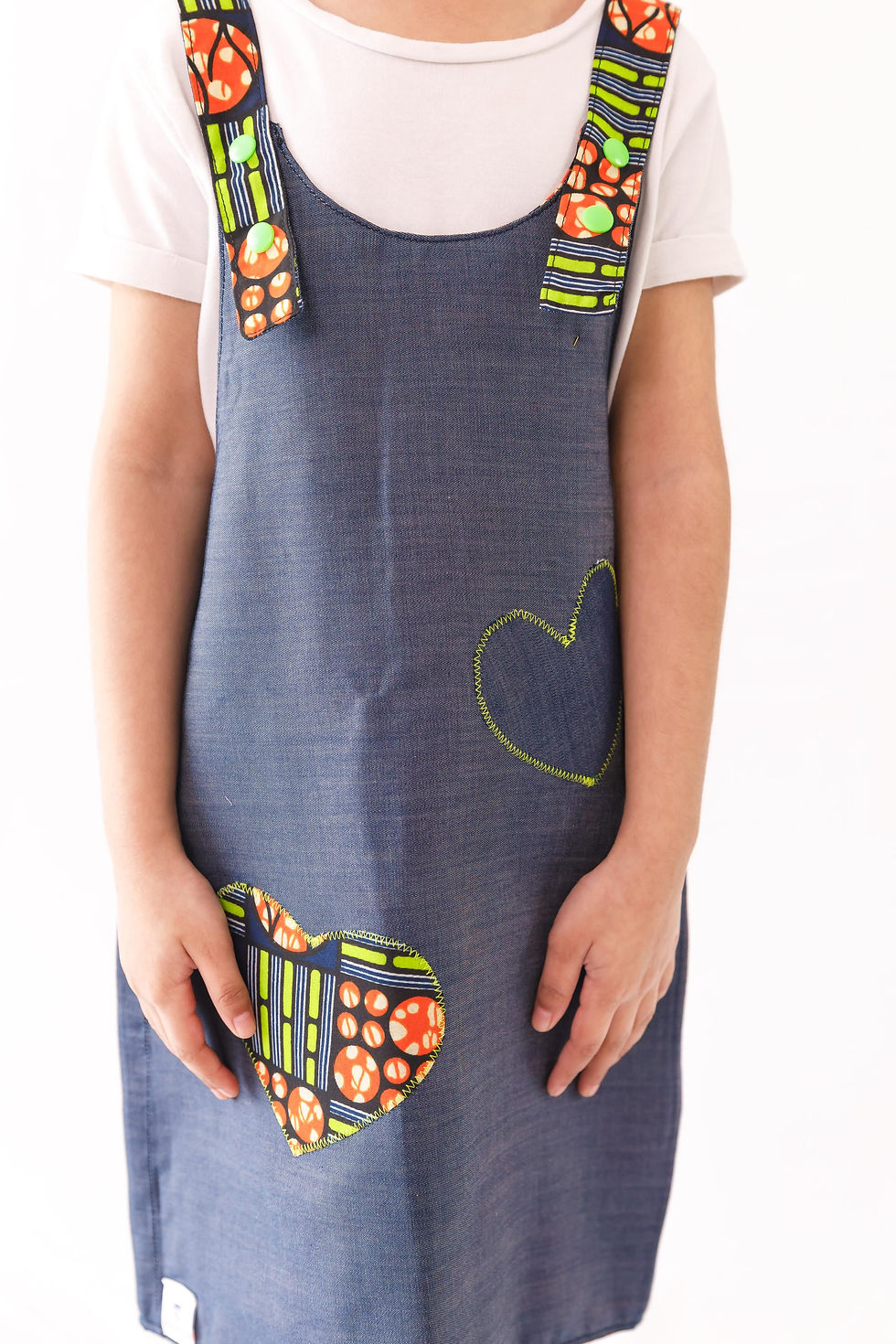 Thumbnail: reversible pinafore features denim on one side and a wonderful orange and bright green wax print on the other reverse