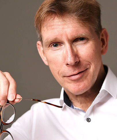 Coach Peter Vollmer, eine Brille in der Hand, lächelnd