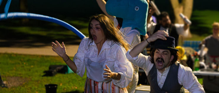 Twelfth Night: Year 6 of hte oath. A man and a woman are staring at something off-camera, both look shocked and wet. Behind them there is someone wearing a whale head