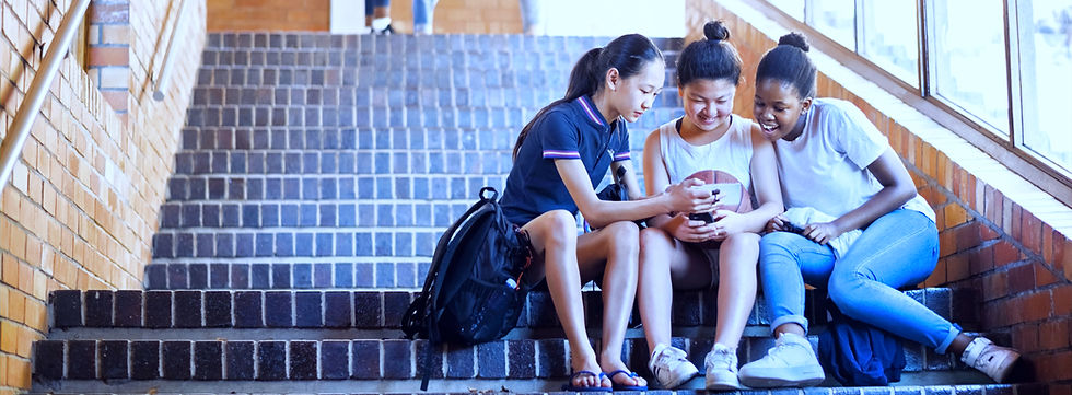 3 meisjes zittend op een trap van schoolgebouw