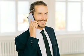 Glücklicher Mann im Anzug am Telefon nachdem er sich mit der Stressbewältigung für Führungskräfte beschäftigt hat.