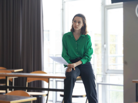 Une coach assise sur une table de la classe pour écouter