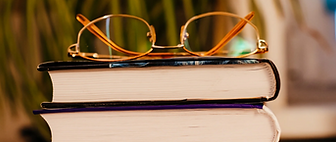 a stack of books with a pair of glasses on top - symbol for trainings/events