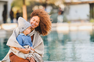 Mom holding toddler next to pool