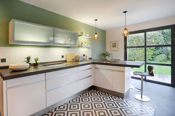 cuisine, mur vert kaki, sol béton ciré et carreaux de ciment géométriques, luminaires en verre fumé